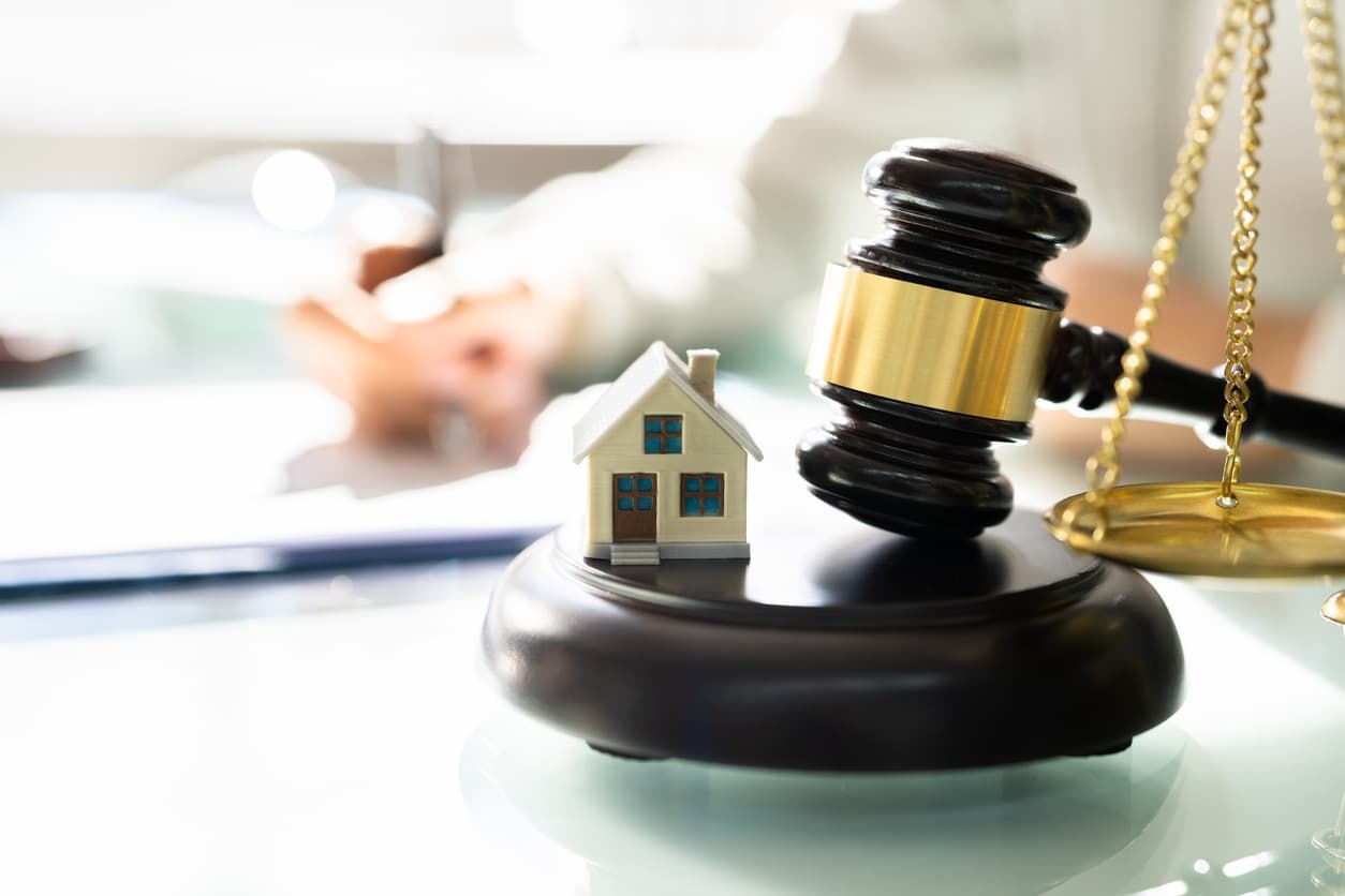 Gavel, house model, and scales of justice representing estate planning and property inheritance.
