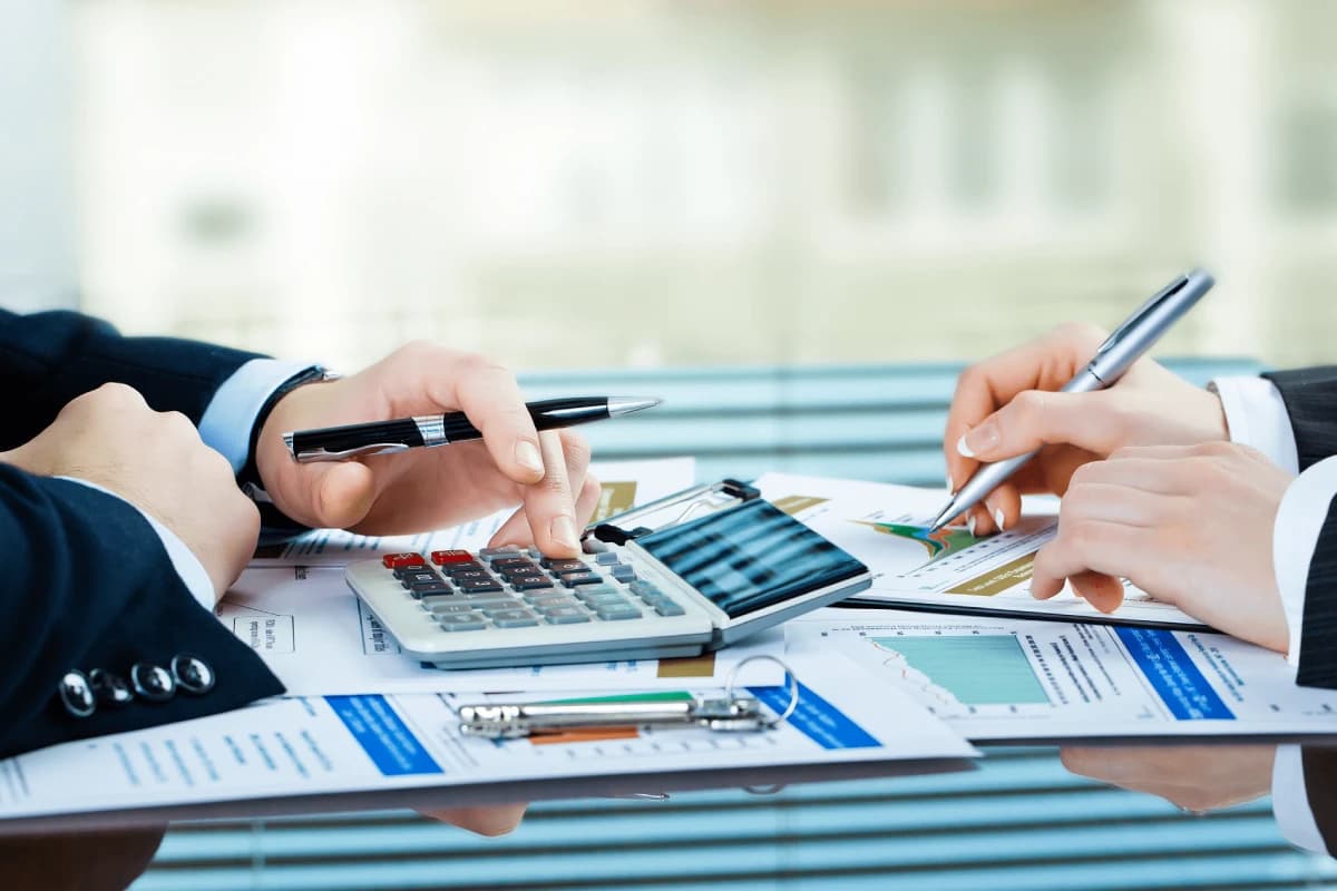Professionals reviewing financial documents, calculator, and business records during a planning meeting.